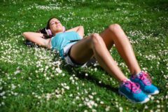 female jogger with headphones in field of clover